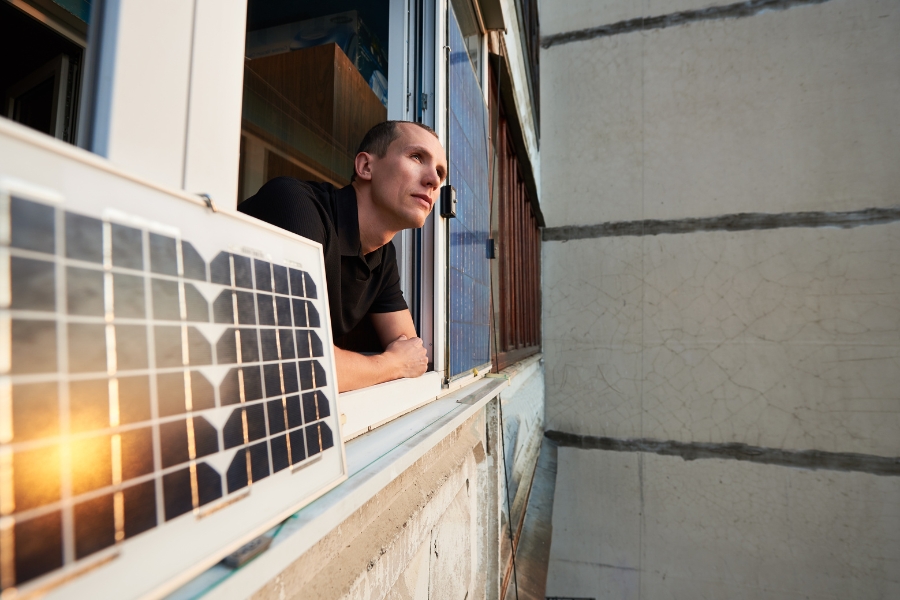 solar pro main balcony solar installation man looking out window beside balcony solar panel